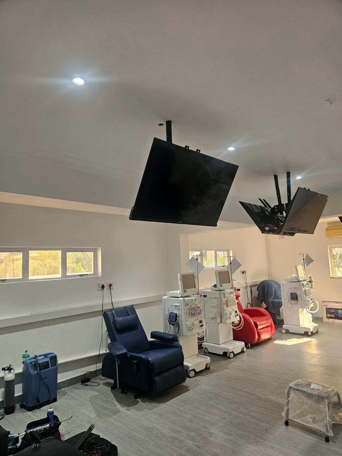 Multiple ceiling-mounted screens with adjustable arms in a clinical treatment room