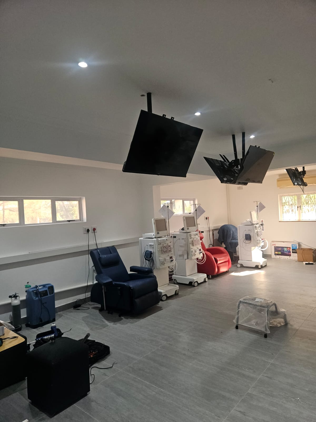 Ceiling-mounted televisions installed above treatment chairs in a medical facility